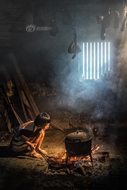 《穷人的孩子早当家》摄影：@三色堇lisa 广西河池市南丹县里湖乡岜地村是白裤瑶族同胞居住地，属于高山上的贫困山区，这里的村民们过着几乎原始的生活，我们到访的这户人家，正好看到小姑娘放学后帮家里人做饭，小小年纪就要为家人分忧，不由得让我们感慨万千。.jpg